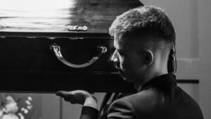 A group of boys following funeral etiquette rules and putting up their friend's coffin in grief