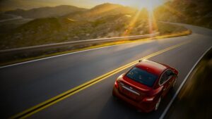 A sleek red car cruises on the road trip, showcasing its horsepower and torque