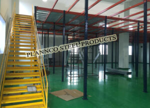 Modular mezzanine floor with steel framework and yellow staircase installed by Plannco Steel Products.