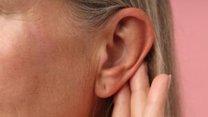 Close-up of an adult ear with fingers touching the earlobe